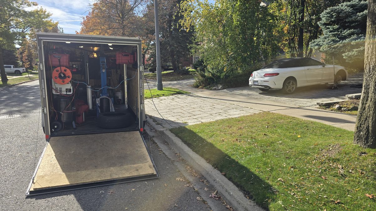 Inside the Sparky X mobile tire shop — service trailer open at a customer's driveway, ramp down, tire and equipment on board