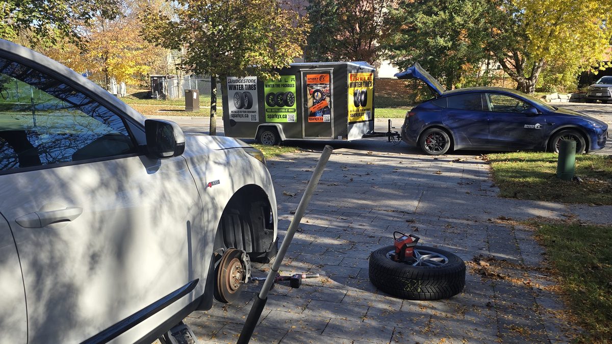 Sparky X seasonal tire changeover at a customer's home — front wheel off, vehicle safely supported, tools laid out