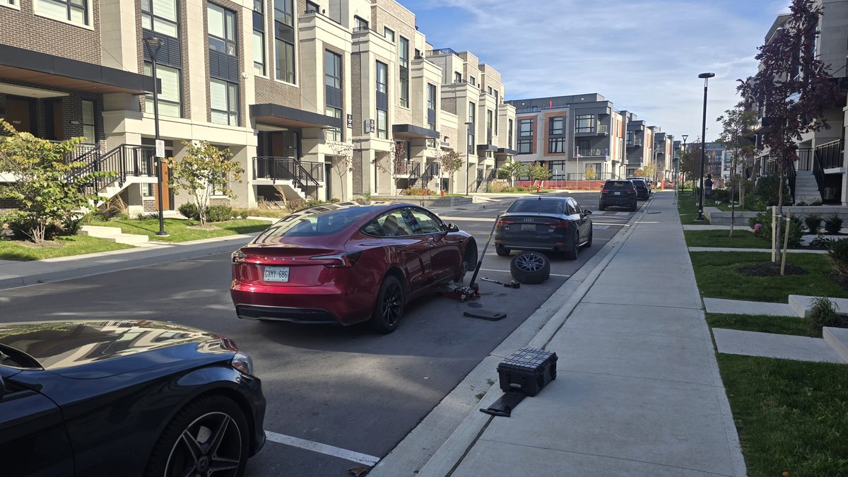 Sparky X Tesla tire service in a customer's driveway — red Tesla with its wheel off, replacement tire and tools beside the car
