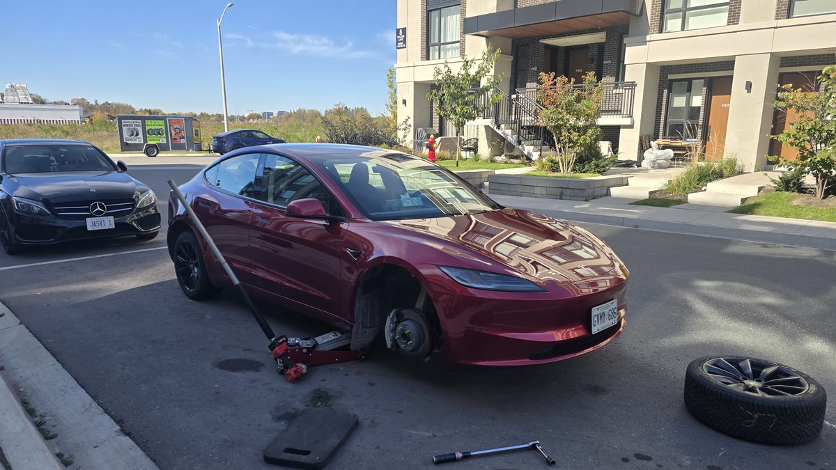 Premium car tire service by Sparky X — a red Tesla with its front wheel removed during a tire change at the owner's home